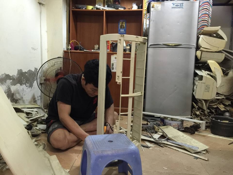 Anh Hiệu đang vệ sinh phần nhựa cho một chiếc máy lạnh cũ.