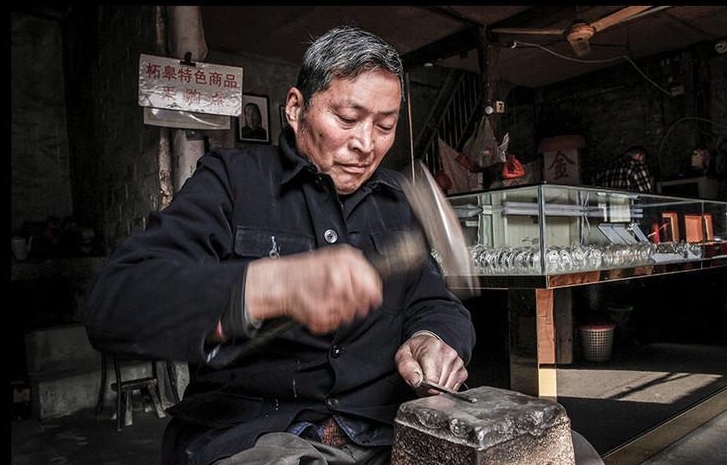 Người thợ 64 tuổi dùng búa để tạo hình cho một thanh bạc.