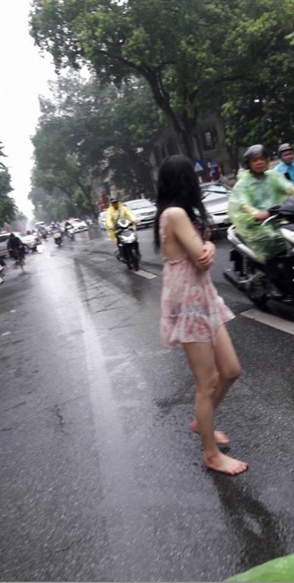 Hành động quá khó hiểu của cô gái giữa phố Hà Nội ngày mưa - Ảnh 1.