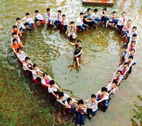 hoc-sinh-xep-hinh-trai-tim-chup-anh-ky-yeu-giua-san-truong-ngap-nuoc