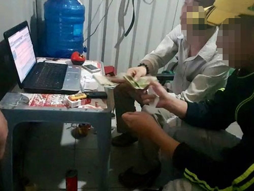  Lâm (ngồi bên trong) nhận tiền cá độ trận Pháp gặp Romania ngay tại căn phòng nằm cạnh quán cà phê ở gần cầu Bùi Đình Túy. (Ảnh cắt từ video do phóng viên thực hiện)Ảnh: LÊ PHONG 