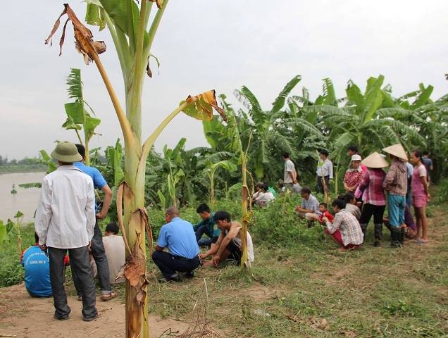 Nhiều người dân ngồi trên bờ cầu nguyện cho cơ quan chức năng sớm tìm thấy cháu Duy