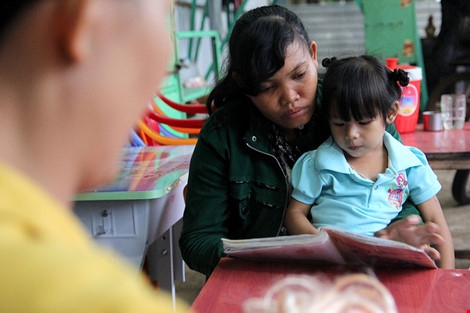 Bé Ngọc Yến chạy đến đùa giỡn bên mẹ nuôi . Ảnh: HOÀNG GIANG