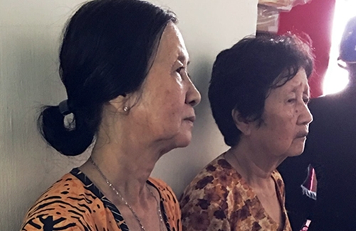 Bà Lê đứng (bên trái) thất thần nhìn mọi người lo hậu sự cho 6 người trong gia đình em trai. Ảnh: Phúc Hưng