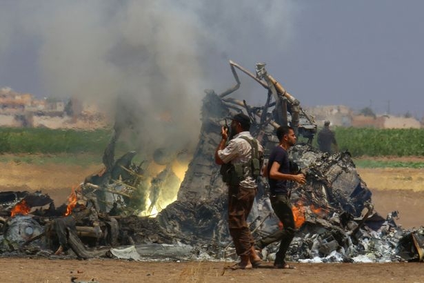 Men-inspect-the-wreckage-of-a-Russian-helicopter-that-had-been-shot-down-in-the-north-of-Syrias-reb