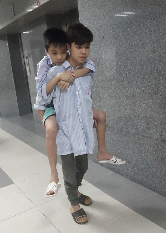  Em trai không đi lại được, Hùng thường xuyên cõng dù không được phép. Ảnh: P.Thuận 