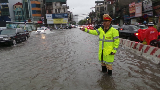  Đại tá Đào Vịnh Thắng trực tiếp lội sông, hướng dẫn, điều khiển giao thông trong cơn bão chiều qua 19/8 - cũng là ngày truyền thống của lực lượng Công an nhân dân. (Ảnh: Tiến Nguyên) 