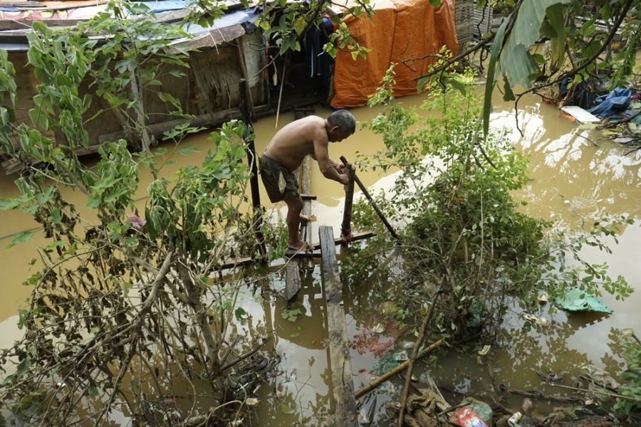  Một người dân của xóm thuyền bè dùng những cây gỗ trôi nổi trên sông làm lại chiếc cầu nối giữa bờ và nhà thuyền. 