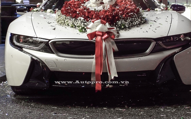  Ở phần đầu xe chiếc BMW i8 trở nên lộng lẫy khi được trang trí bó hoa cưới cỡ lớn trên nắp capô, chính giữa có cặp gấu bông xinh xắn. Bên cạnh đó còn có nơ cưới được kéo dài từ mũi xe đến cản va trước khá bắt mắt. 