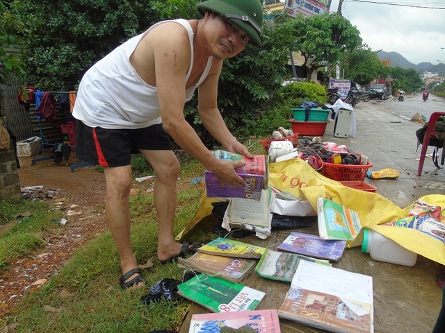 Anh Hồ Tứ tại xã Sơn Trạch đang lau dọn, phơi những cuốn sách bị ướt cho đứa con đang học lớp 8