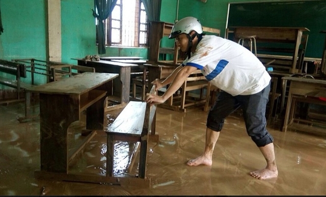 Các giáo viên và học sinh Trường THCS Văn Hoá lau chùi bàn ghế và phòng học sau lũ