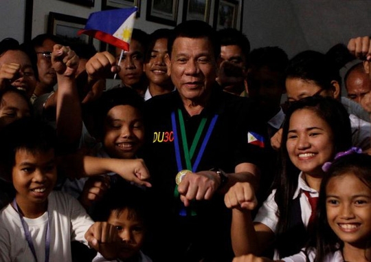  Tổng thống Duterte chụp ảnh cùng trẻ em trong chuyến thăm TP Tarlac ngày 11-12. Ảnh: REUTERS 