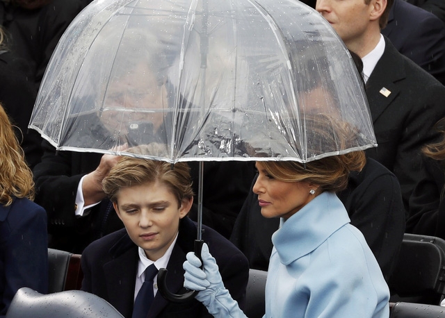 Đệ nhất phu nhân Melania Trump che ô cho con trai Barron Trump trong lúc ông Trump phát biểu trên sân khấu.