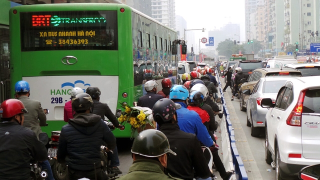 Xe máy len lỏi giữa dải phân cách cứng và xe buýt nhanh.
