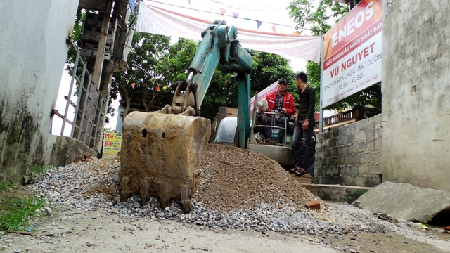  Người dân huy động máy xúc để di chuyển đống đá, sỏi chặn lối đi trước khi Chủ tịch TP Hà Nội Nguyễn Đức Chung về xã. 