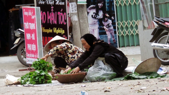 Hai cụ già vừa bày hàng, vừa vui cười trò chuyện.