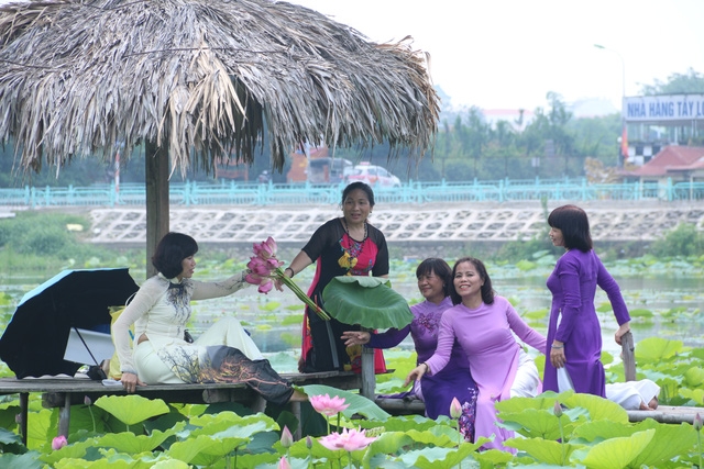 Không chỉ có các bạn trẻ thích chụp ảnh cùng hoa sen, nhiều phụ nữ trung tuổi cũng ra hồ tạo dáng với hoa sen bên áo dài truyền thống để ghi lại những kỷ niệm.