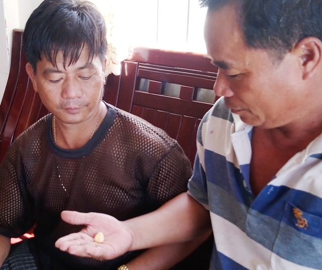  Anh Nam (trái) đang cho khách xem vật lạ được cho là ngọc ốc quý hiếm. (Ảnh: CTV) 
