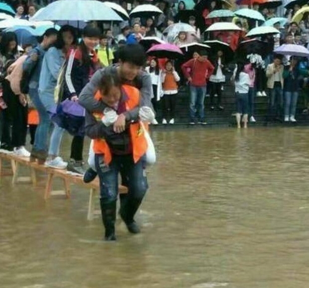 Một nam sinh để nữ lao công cõng qua khu ngập ở Đại học Lục Bàn Thủy, Trung Quốc ngày 15.6 /// Chụp từ SCMP