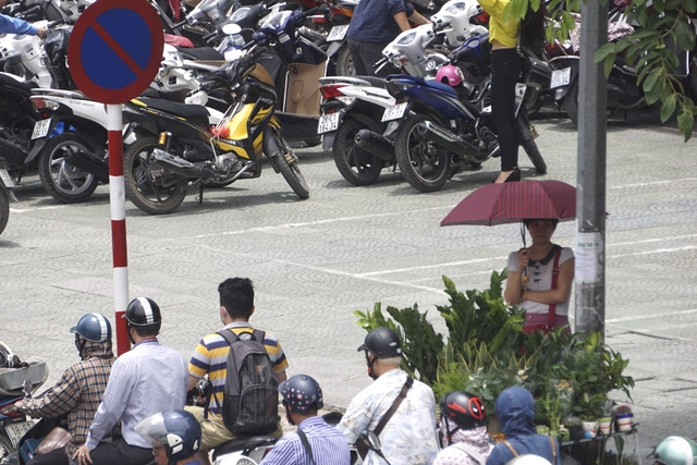  Một người đang tận dụng bóng mát nhỏ nhoi trên đường phố nóng như chảo lửa. 