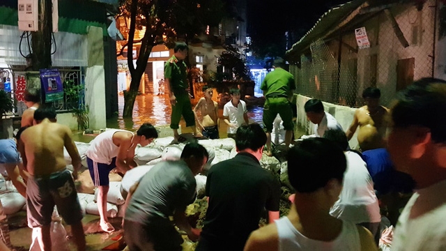 Người dân và cơ quan chức năng tích cực đắp bao cát, đất để ngăn chặn dòng nước