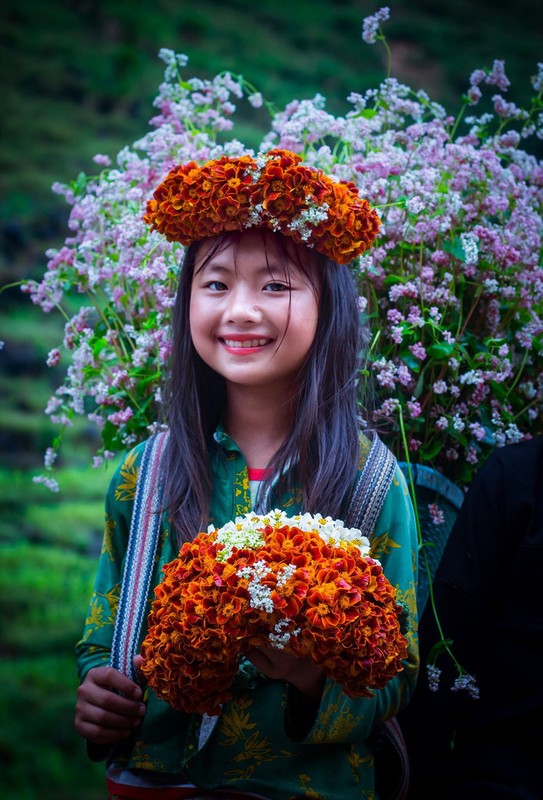Cô bé gây sốt với hình ảnh đeo gùi hoa đứng ở dốc Thẩm Mã (Hà Giang) với gương mặt xinh xắn và nụ cười rạng ngời.