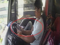 Tài xế dùng chân điều khiển xe đầu kéo chạy trên cao tốc, tay cầm điện thoại lướt TikTok